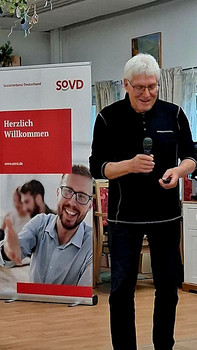 Mann steht mit Mikrofon in der Hand.