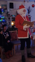 Ein Weihnachtsmann liest aus einem Buch.