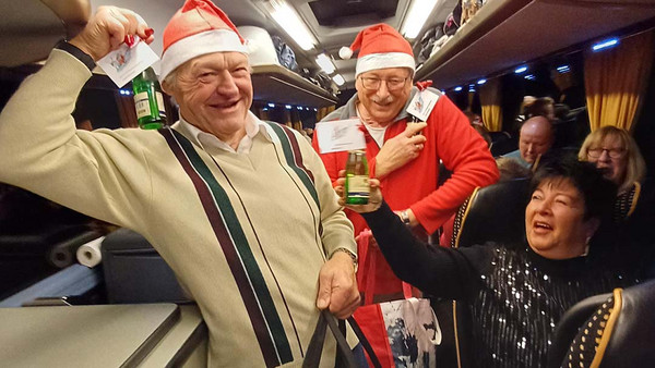Frau prostet zwei Weihnachtmännern im Bus zu