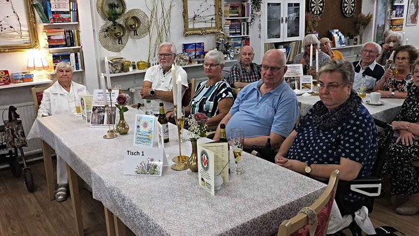 Zuhörer*innen sitzen am Tisch