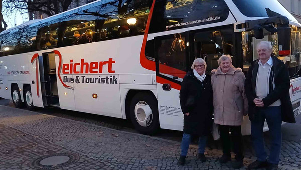 Drei Leute vor einem Reisebus