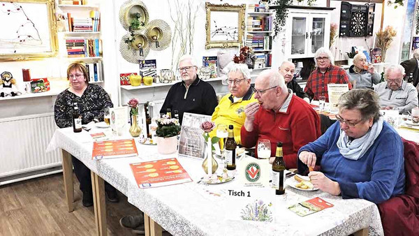 Männer und Frauen essen am Tisch.