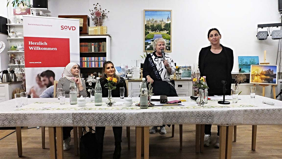 Vier Frauen an einem Tisch, im Hintergrund ein SoVD-Plakat.