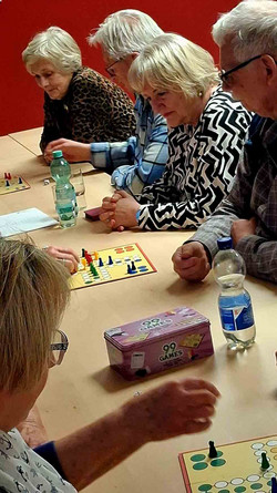 Männer und Frauen sitzen an Brettspielen.