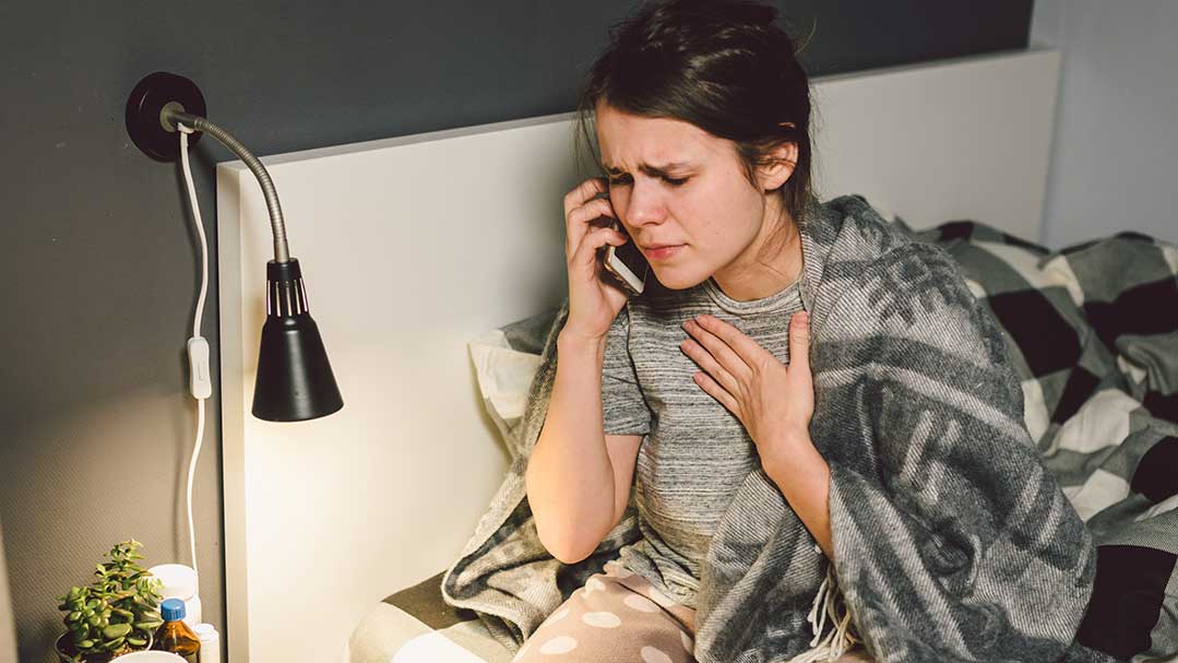 Frau telefoniert und hält sich an den Hals.