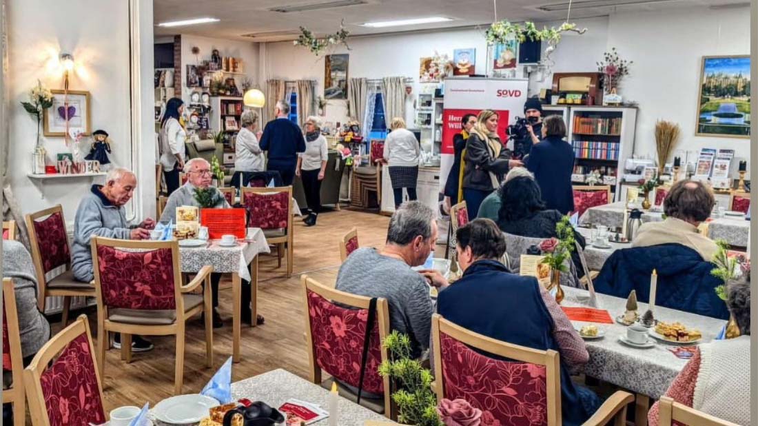 Veranstaltungssaal, im vorderen Teil spricht eine Frau mit einem Filmteam. 