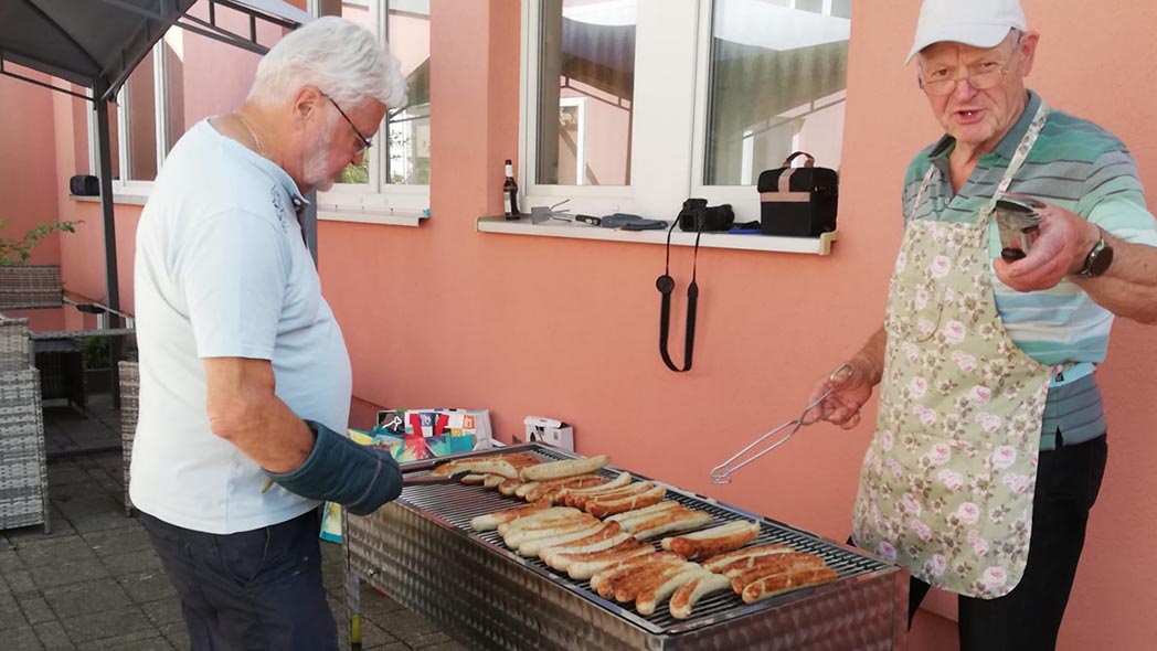 Zwei Männer grillen Würstchen
