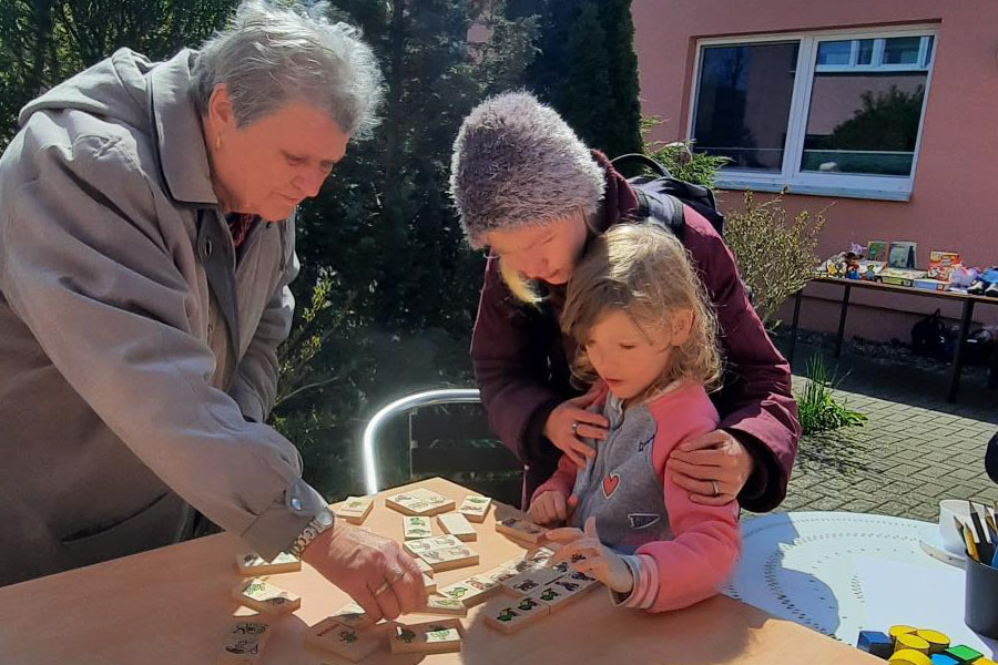 Ältere Frau hilft Mutter mit Kind beim Spielen